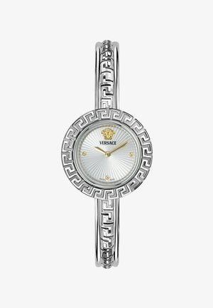 Zilverkleurig Versace-horloge met lunette en armband met Grieks sleutelmotief, gouden wijzers en Medusa-logo op een zilverkleurige zonnestraalwijzerplaat.