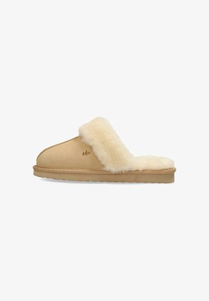 Chausson beige avec doublure en peau de mouton, design à dos ouvert, extérieur lisse et semelle texturée pour une bonne adhérence. Présente des détails de logo discrets.