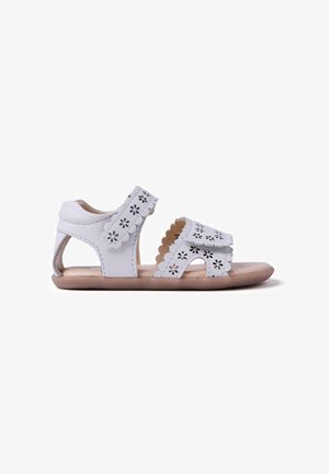 Sandali in pelle bianca con intagli floreali, bordi smerlati, retro aperto e suola beige. Tessuto morbido e design leggero.