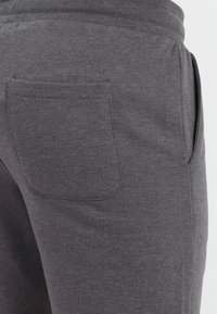 Dark grey sweatpants made of soft material, featuring a back pocket and elastic waistband. Texture appears smooth with subtle stitching details.