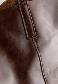 Braune Leder-Tote mit glatter Textur, gesteppten Nahtdetails und einem flachen Tragegurt.