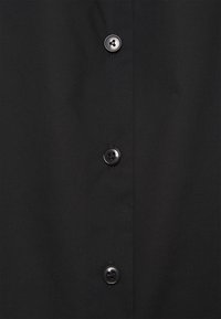 Černá košile s hladkým materiálem a pěti černými knoflíky vpředu. Jednoduchý design bez vzorů nebo textur.