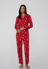 Rode pyjama set met lange mouwen en broek, versierd met een speelse print van vakantie-thema iconen in blauw en wit. Zachte stof.