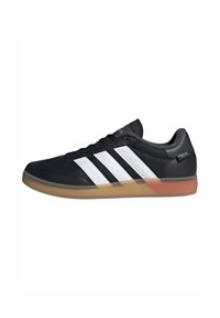 Black athletic shoe with a textured mesh upper, features three white stripes design, a gum rubber sole, and a padded collar.