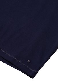 Dunkelblauer Baumwollstoff mit einer glatten Textur, der einen abgerundeten Saum und ein kleines, rundes Markenetikett in der Nähe des Randes aufweist.