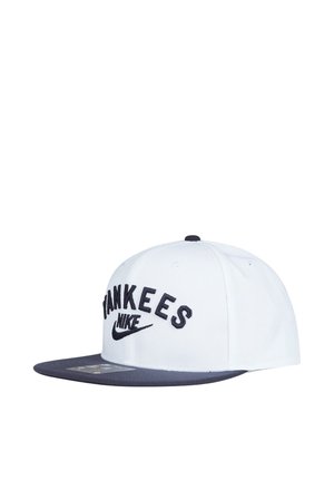 Cappellino da baseball bianco e blu navy con scritta "YANKEES" e logo Nike ricamati in nero sul davanti, visiera piatta, mostrato su sfondo bianco.