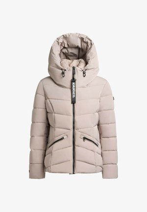 Vadderad beige jacka med hög krage och stor huva, med dragkedjestängning och två fickor med dragkedja i sidorna. Slarvigt utseende, kviltad design.