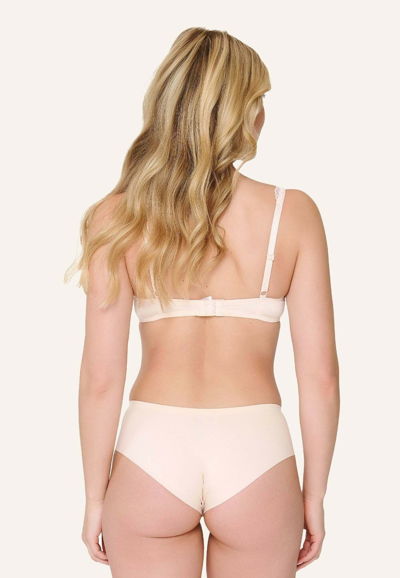Sujetador de encaje beige con tirantes ajustables y cierre de gancho, combinado con unas bragas beige suaves de corte medio y diseño sin costuras.