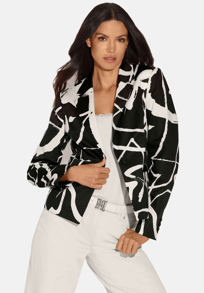 Zwart-wit gestreepte blazer met een getailleerde pasvorm, met notch-lapels en een enkele knoopsluiting. Gecombineerd met een lichte top en witte broek.