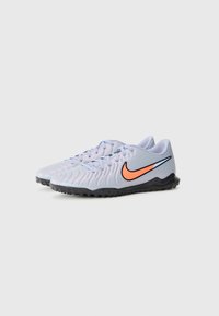 Scarpe sportive Nike con una tomaia sintetica di un viola chiaro, design testurizzato, logo swoosh rosa-arancio e suola testurizzata nera.