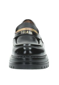 Mocassini in vernice nera con punta rotonda, ampia fascia con logo dorato e suola strutturata. Decorati con cuciture a vista.