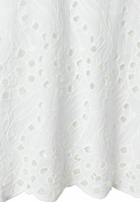 Weißer gestickter Stoff mit komplexen floralen Designs und Ausschnittmustern. Mit einer strukturierten, gewellten Kante am unteren Rand.