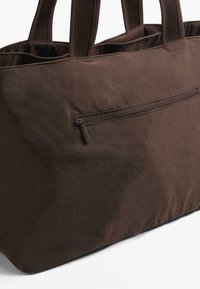 Brown fabric tote bag with a smooth texture, featuring dual handles and a front zip pocket for secure storage.