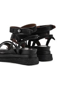 Černé kožené sandály s několika pásky, obtočeným kotníkem a nízkým podpatečkem. Podešev má strukturovaný design pro lepší přilnavost.