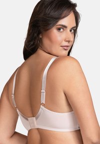 Reggiseno rosa chiaro in tessuto morbido, con spalline in satin regolabili e chiusura a gancio. Presenta coppe senza cuciture e dettagli di cucitura discreti.