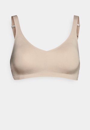 Beige saumoimaton rintaliivi, jossa on leveät hihnat ja sileä pinta. Ominaisuuksiin kuuluu matala V-kaula-aukko ja säädettävät kiinnitysominaisuudet.