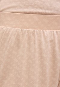 Κοντινό πλάνο μπεζ υφάσματος με ραφή με λάστιχο και λείο τμήμα στη μέση.