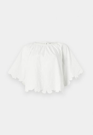 Haut en coton blanc avec un décolleté rond et des manches courtes évasées. L'ourlet festonné présente une broderie florale, créant un design texturé.