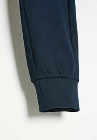 Ciemnoniebieski bawełnowy mankiet bluzy, z prążkowaną teksturą, elastycznym dopasowaniem i gładkim wykończeniem. Prosty, czysty design bez widocznych wzorów.