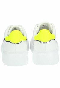 Sneakers bianchi con tomaia in pelle liscia, tacco posteriore giallo brillante con accento argentato e una suola bianca spessa.