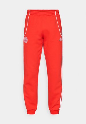 Crvene trenirke s elastičnom pasicom, bijelim stranama i detaljima logotipa na kuku i donjem dijelu noge. Izrađene od mekog materijala s rebrastim manžetama.