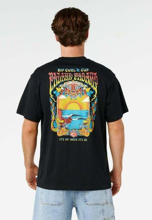 Mężczyzna w czarnej koszulce z kolorową grafiką zachodu słońca nad oceanicznymi falami oprawionymi przez smoki oraz tekstem „Rip Curl Cup” i „It's on when it's on.”