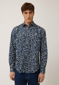 Marineblauwe overhemd met knopen en een wit bloempatroon, lange mouwen en een kraag. De stof lijkt glad met een lichte glans.