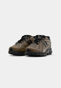 Men's running shoes in tan and black. Features mesh upper, padded collar, textured overlays, and a robust rubber sole for traction.