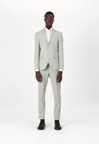 Šviesiai pilkas kostiumas, pritaikytas tinkamai, su dviem mygtukais ir išpjauta apykakle. Derinamas su balta marškiniais ir juodais batais. Lygus paviršius.