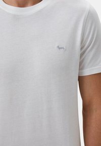 T-shirt bianco in cotone con collo rotondo, maniche corte e un piccolo logo ricamato di un bassotto azzurro sul petto.