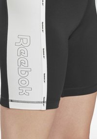 Czarno-białe szorty sportowe z logo Reebok, o gładkiej fakturze i kontrastowym panelu kolorystycznym po boku.