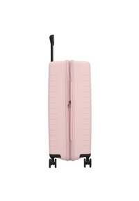 Valigia rigida di colore rosa chiaro con superficie texturizzata e scanalature verticali; dotata di un manico telescopico nero e due ruote.
