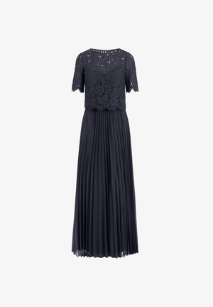 Marineblauwe jurk met een kanten bovenstuk en korte mouwen, en een geplooide chiffon rok die tot aan de enkels valt.