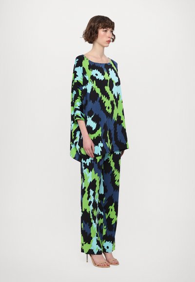 Colorful loose-fit ensemble featuring a geometric pattern in blue, green, and black. The top has wide sleeves; paired with matching trousers.