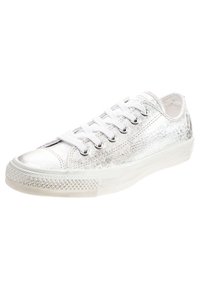 Metallisch silberner Low-Top-Sneaker mit strukturiertem Obermaterial, weißen Schnürsenkeln, runder Zehenkappe und einem gemusterten Gummi-Sohle.