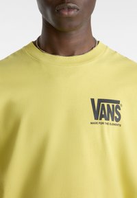Yellow cotton t-shirt with a crew neckline, featuring a black Vans logo on the chest and text "MADE FOR THE ELEMENTS" below.