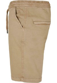 Pantaloni bermuda beige in tessuto con finitura testurizzata. Vita elastica con cordoncino, tasche laterali e una tasca posteriore singola.