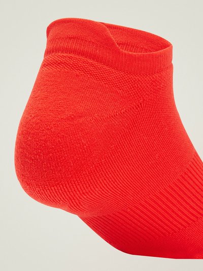 Calcetín de tobillo rojo hecho de una tela texturizada, con patrones acanalados en la parte superior y una textura suave en el cuerpo, destacando un ajuste ceñido.