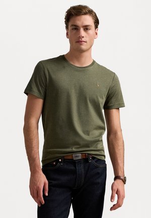 Olijfgroene katoenen t-shirt met een ronde hals, korte mouwen en een klein geborduurd logo op de borst, gecombineerd met donkere spijkerbroek.