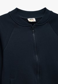 Dunkelblaues Zip-Jacke aus weichem, strukturiertem Stoff. Verfügt über einen gerippten Kragen und Raglanärmel mit einem schlichten Design.