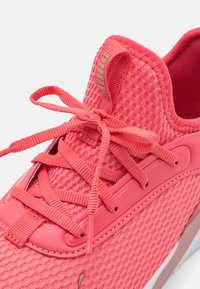 Zapatilla de malla rosa con un upper texturizado, cordones planos y una suela de goma sólida con un acento en contraste. Marca en la lengüeta.