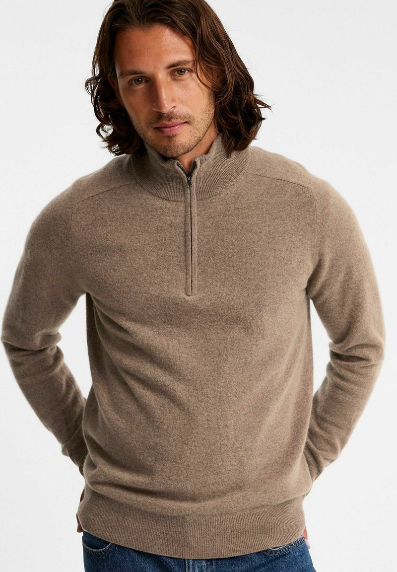 Brauner Reißverschluss-Pullover aus weichem Material, mit hohem Kragen, gerippten Bündchen und figurnaher Silhouette. Schlichtes Design ohne Muster.