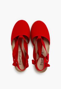 Chanclas de lienzo rojas con puntera redondeada, correas anchas y suela de goma texturizada. El interior es de color beige con una marca impresa.