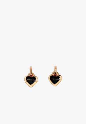 Pendientes en forma de corazón en tono dorado con incrustaciones de esmalte negro y branding grabado, que cuentan con un cierre de aro simple para un uso seguro.