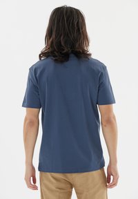 Marinblå t-shirt med kort ärm, tillverkad av bomull, med rund hals och rak nederkant. Slät textur utan framträdande mönster eller detaljer.