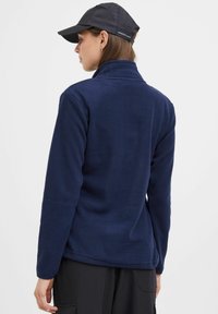 Pull en polaire bleu marine avec un col montant et des manches longues, bénéficiant d'une texture douce et d'une coupe décontractée. La vue arrière montre des détails de couture.
