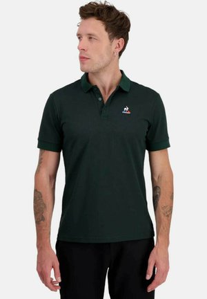 Camisa polo verde oscuro de manga corta, con cuello y un pequeño logo en el pecho. Fabricada con una tela ligera y suave.