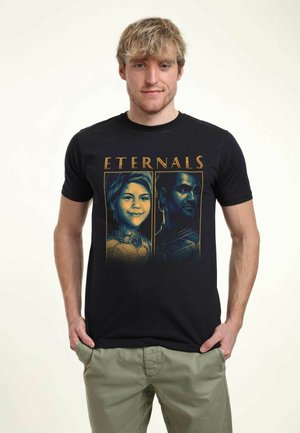 Schwarzes Baumwoll-T-Shirt mit bunten Drucken von zwei Charakteren aus "Eternals", mit dem Titel darüber in goldener Schrift.