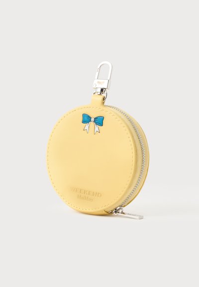 Porte-monnaie rond jaune zippé avec décor de nœud bleu et attache à fermoir argentée en haut.