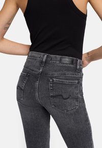 Zwarte denim jeans met een vervaagd uiterlijk, voorzien van gestikte achterzakken en een leren label op de tailleband. Tailored fit ontwerp.